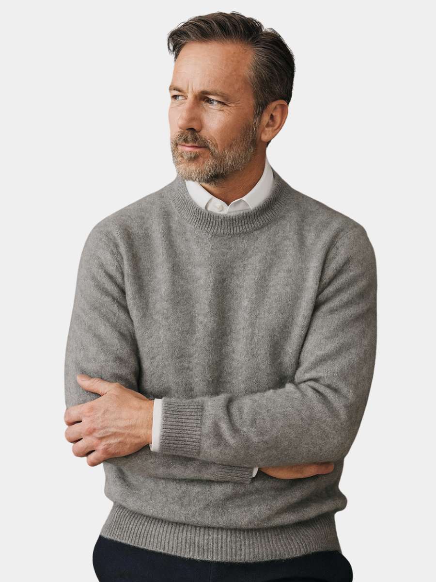 Homme en pull en cachemire gris chiné, bras croisés, col de chemise blanche visible