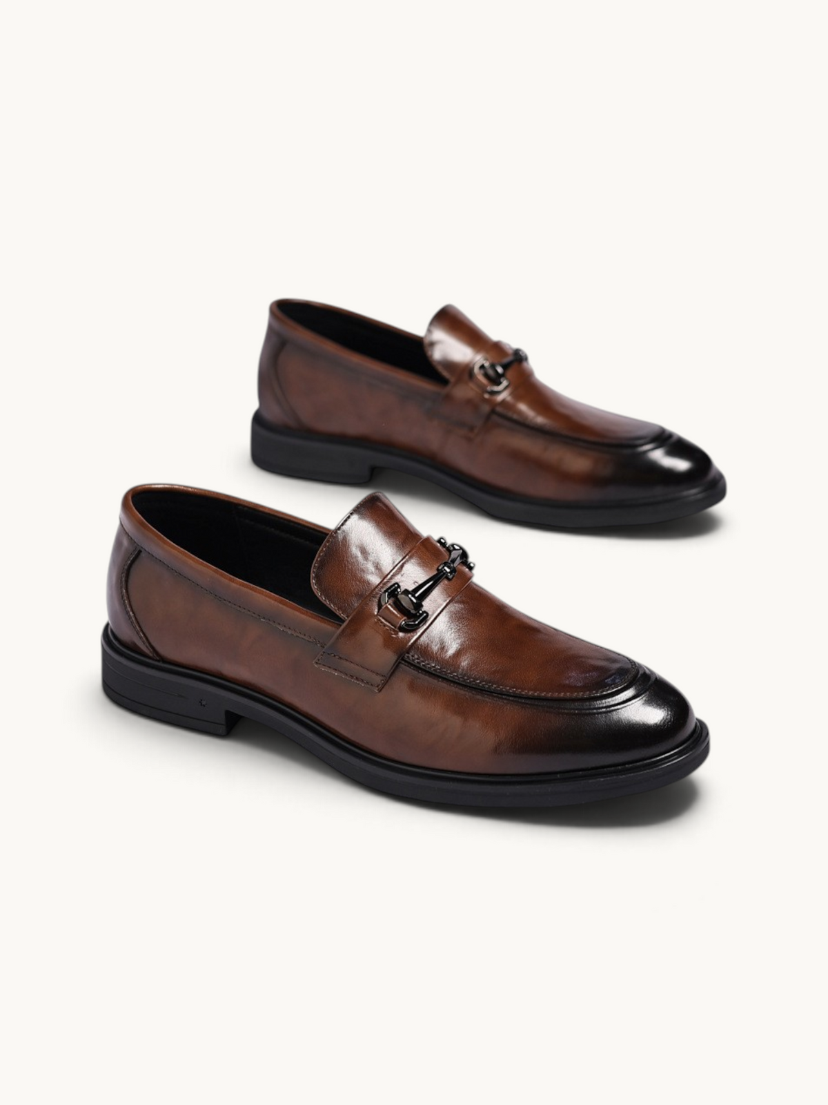 By Old Money brown leather loafers with a polished finish, metal bit detail, and a rounded toe on a white background.