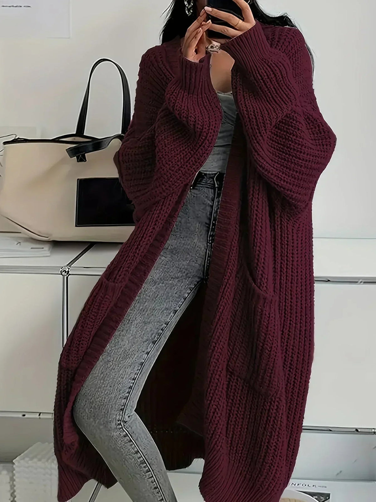 Cardigan long oversize bordeaux en maille épaisse côtelée, porté avec un jean gris