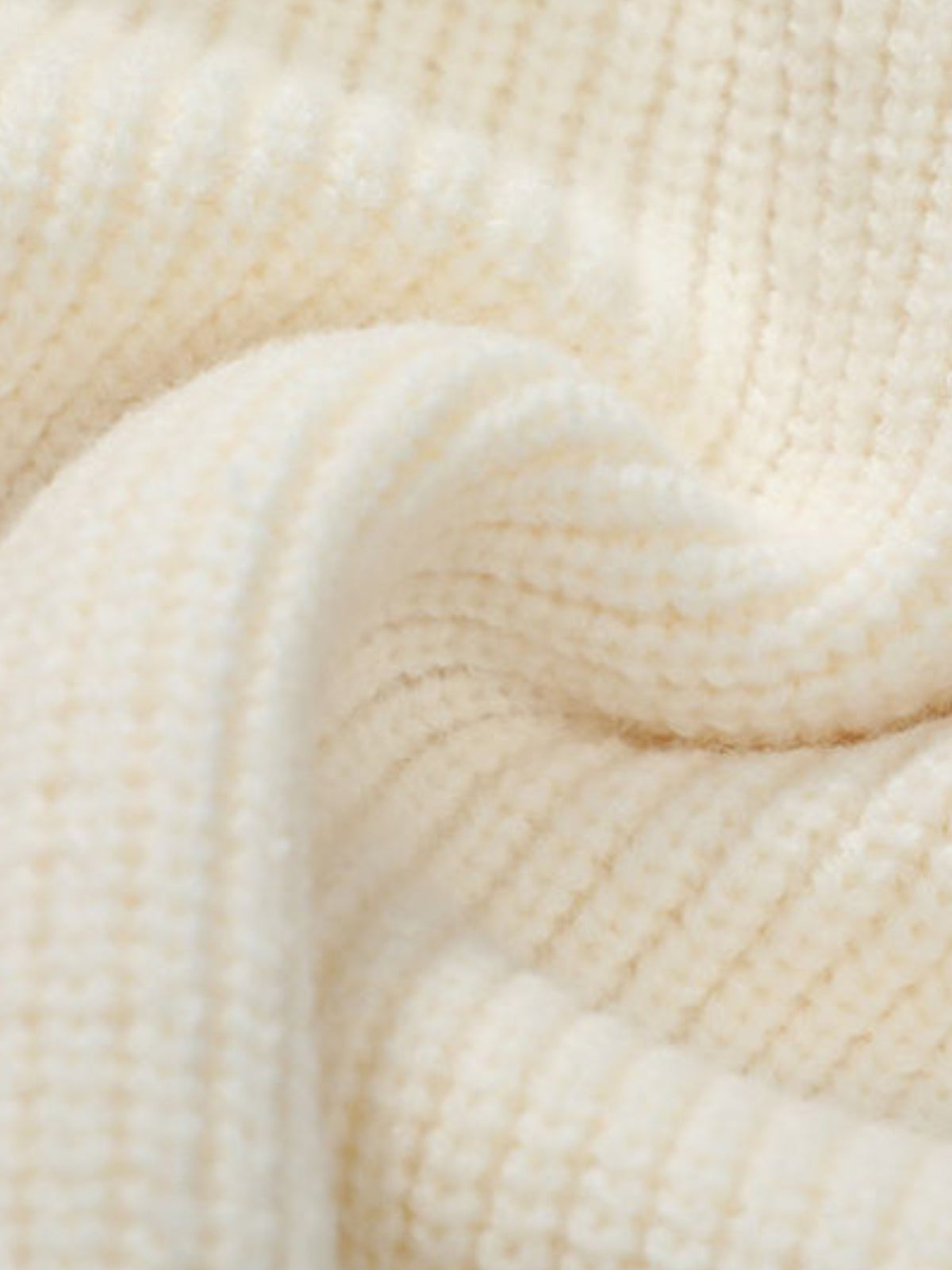 Gros plan sur la grosse maille côtelée crème du cardigan
