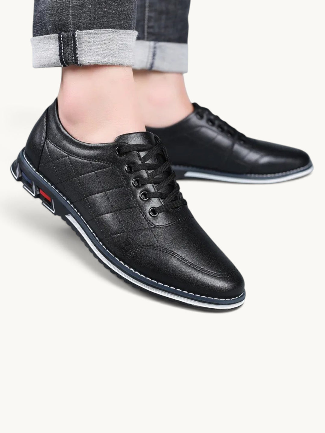 Chaussures basses noires en cuir matelassé avec semelle blanche et bleue, lacées, portées avec jean clair