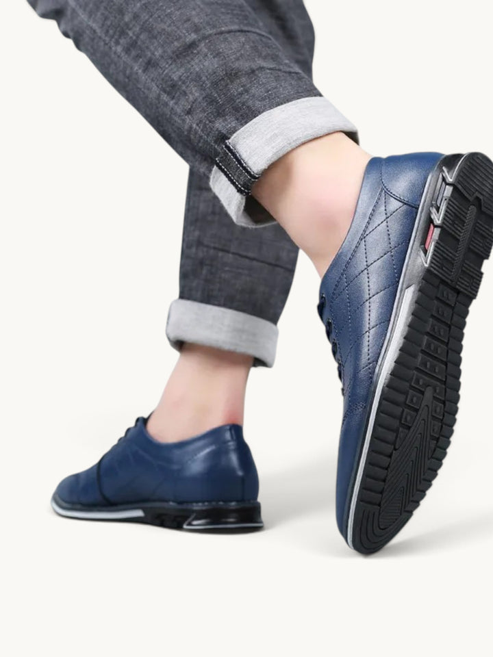 Chaussure basse bleu marine en cuir matelassé avec semelle noire, portée avec jean gris retroussé