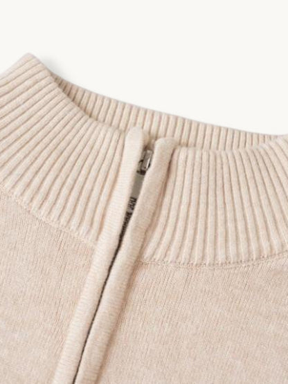 Détail du col zippé d'un pull en maille beige, bord côtes et curseur métallique