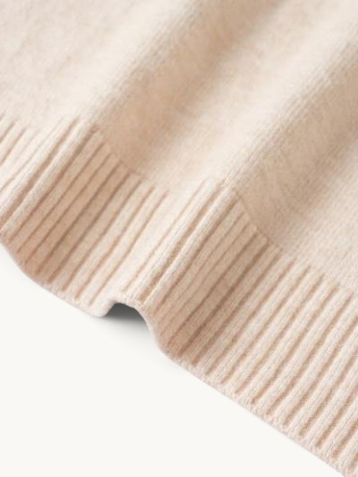 Gros plan sur le bord côtelé du pull en maille beige
