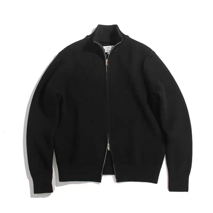 Cardigan noir en maille côtelée à col montant et double zip argenté, posé à plat sur fond blanc
