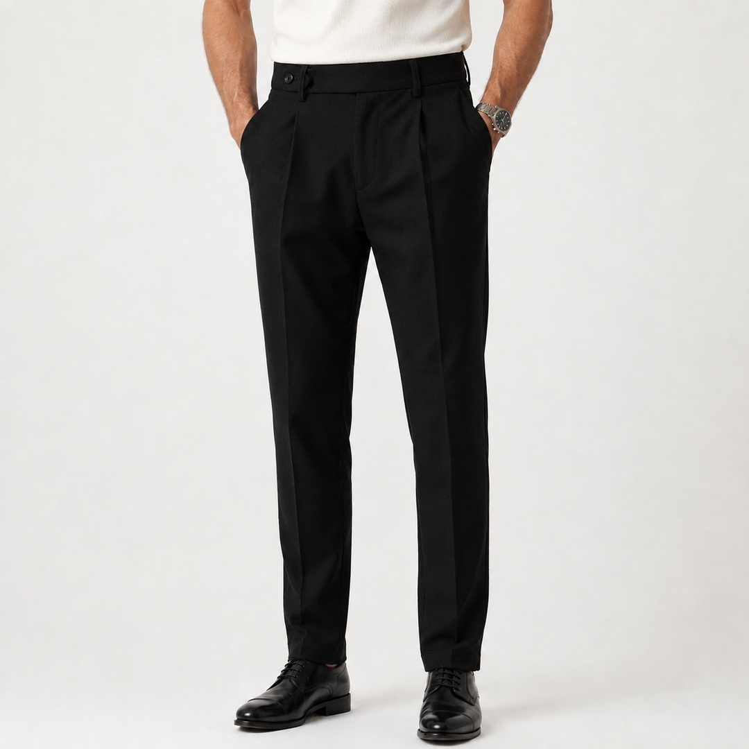 Black tapered trousers with pleats and belt loops, worn by model with cream shirt