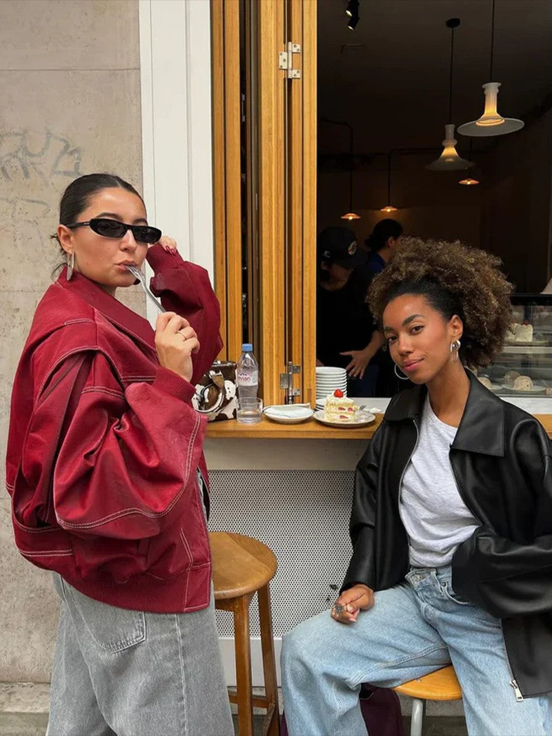 Blouson oversize rouge cerise porté en terrasse de café, vue de trois quarts