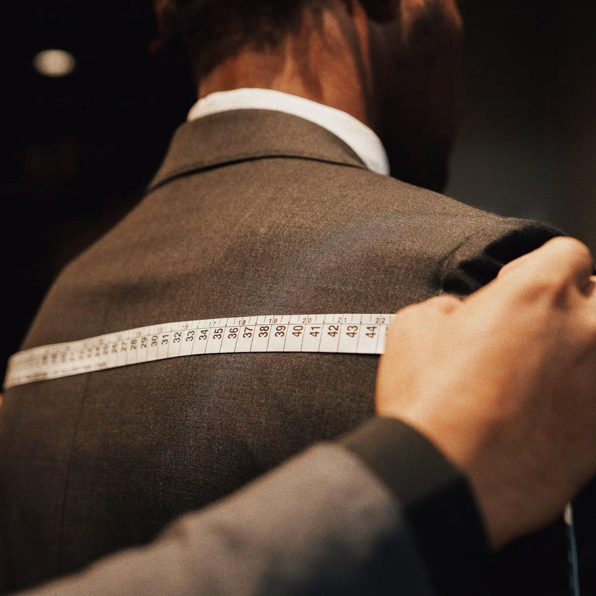 Tailleur mesurant la carrure d'une veste au mètre ruban