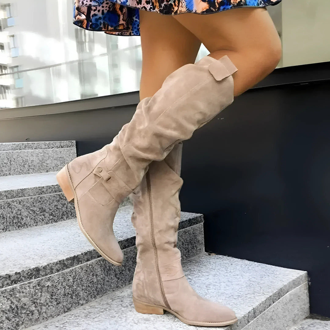 Botte haute beige à tige froissée sur des marches en pierre, de profil