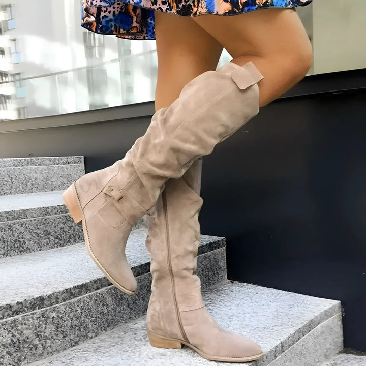 Botte haute beige à tige froissée sur des marches en pierre, de profil