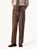Pantalon droit plissé brun en chevrons porté avec une chemise rayée