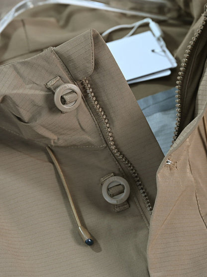 By Old Money beige water-repellent hooded jacket featuring a zip closure, snap buttons, and drawstring hood.