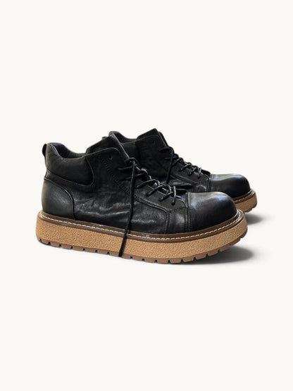 By Old Money black full-grain leather work boots with a thick lugged tan sole and mid-height ankle support.