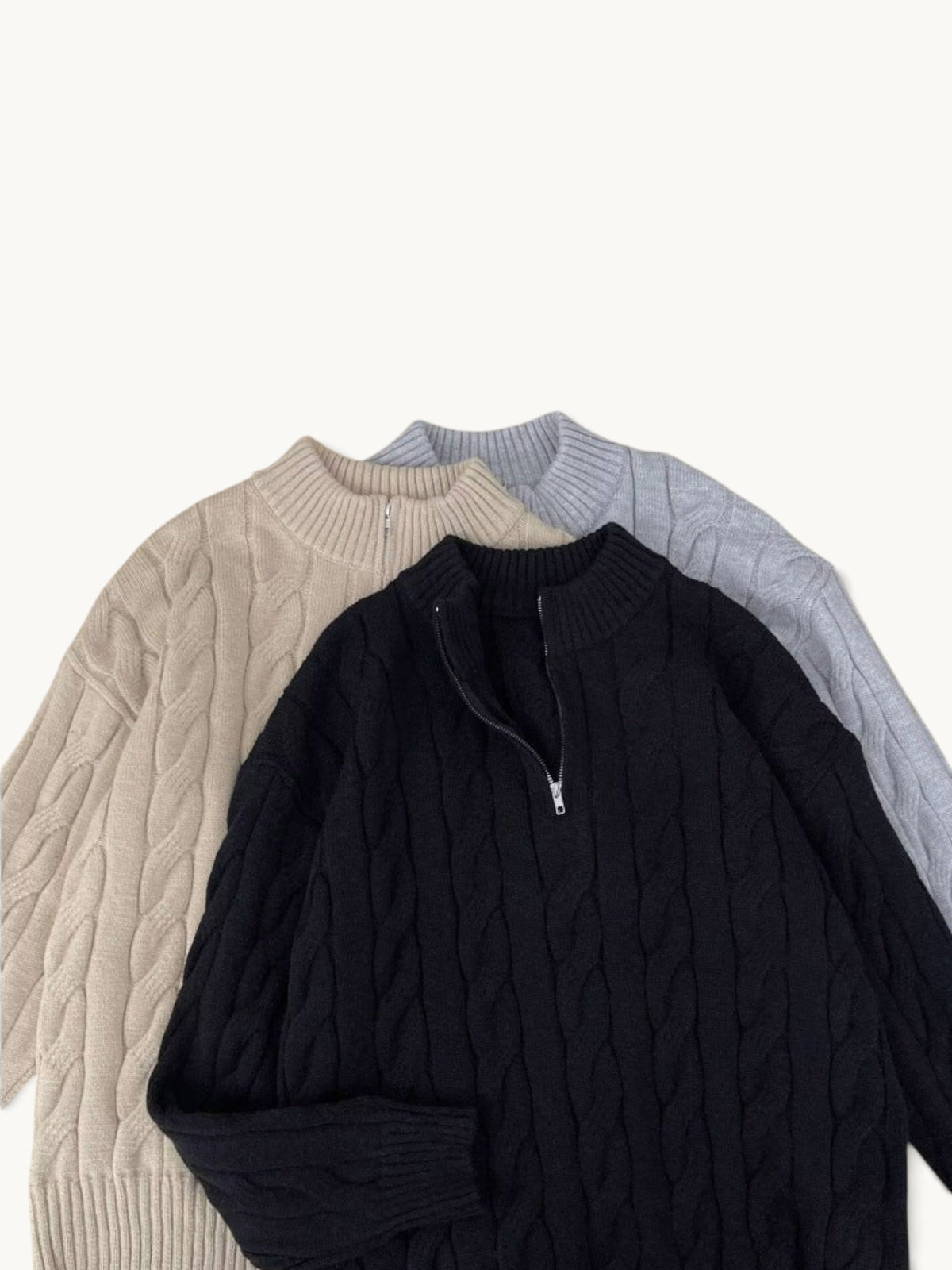 By Old Money cable knit half-zip sweaters in black, beige, and grey with ribbed collars and cuffs.