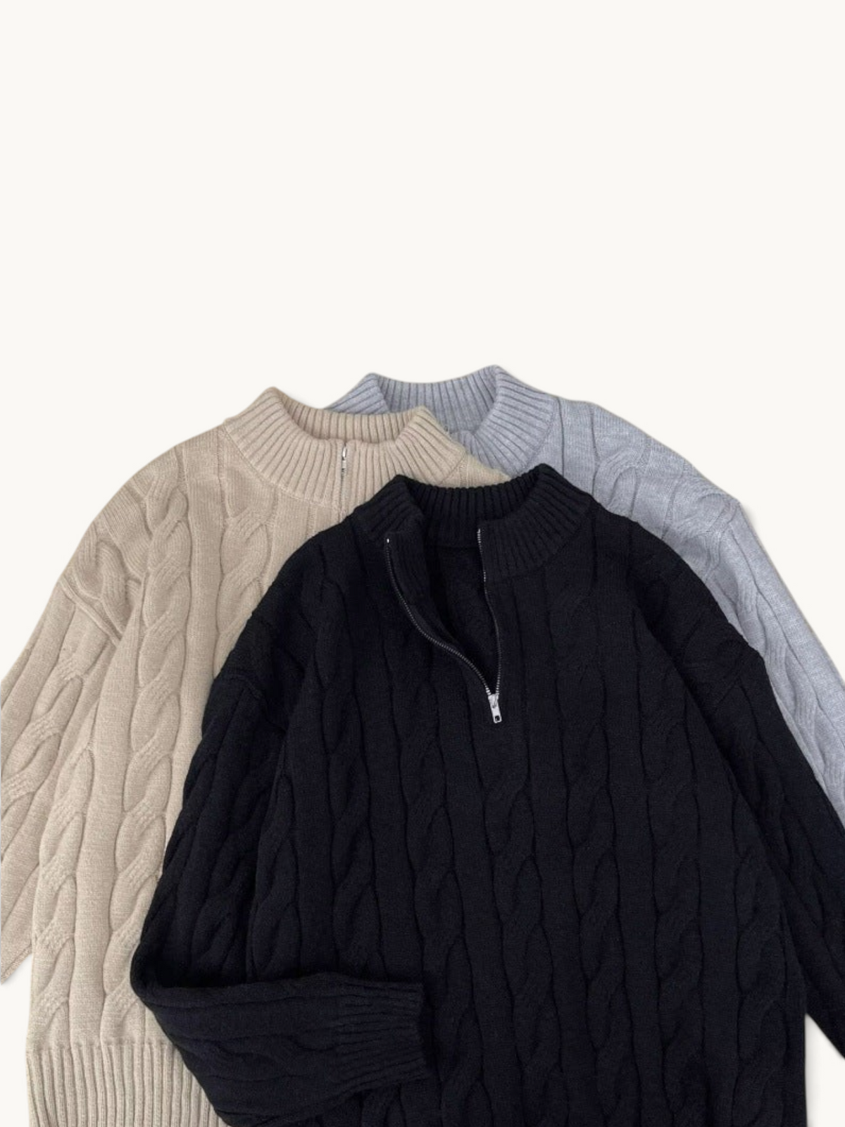 By Old Money cable knit half-zip sweaters in black, beige, and grey with ribbed collars and cuffs.