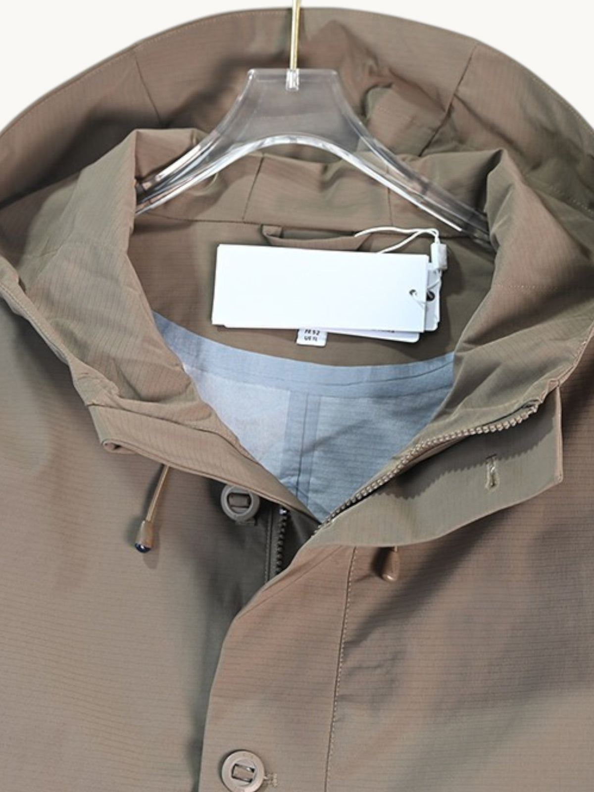 By Old Money water-repellent hooded jacket in taupe with a drawstring hood and snap-button placket.