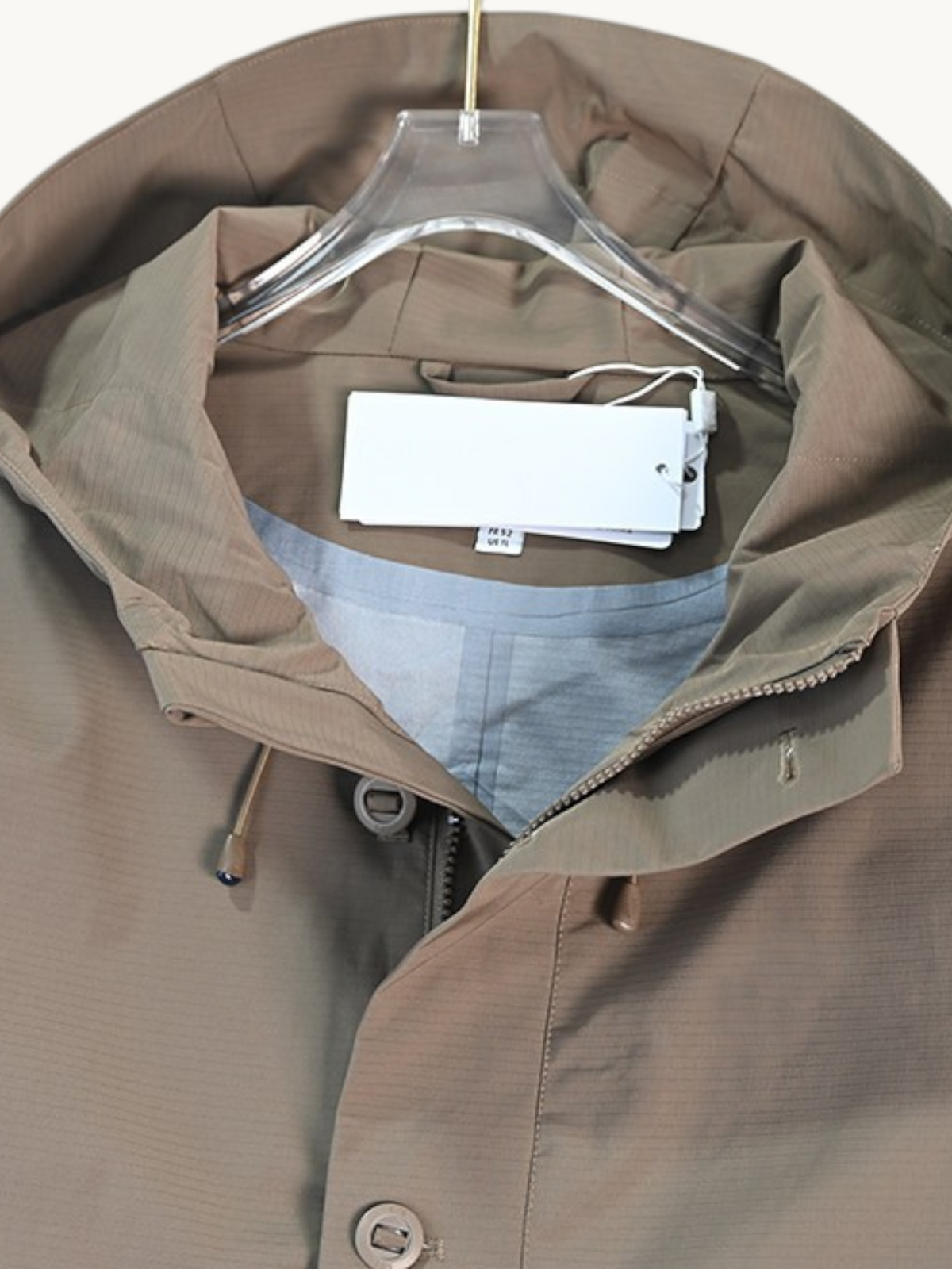 By Old Money water-repellent hooded jacket in taupe with a drawstring hood and snap-button placket.