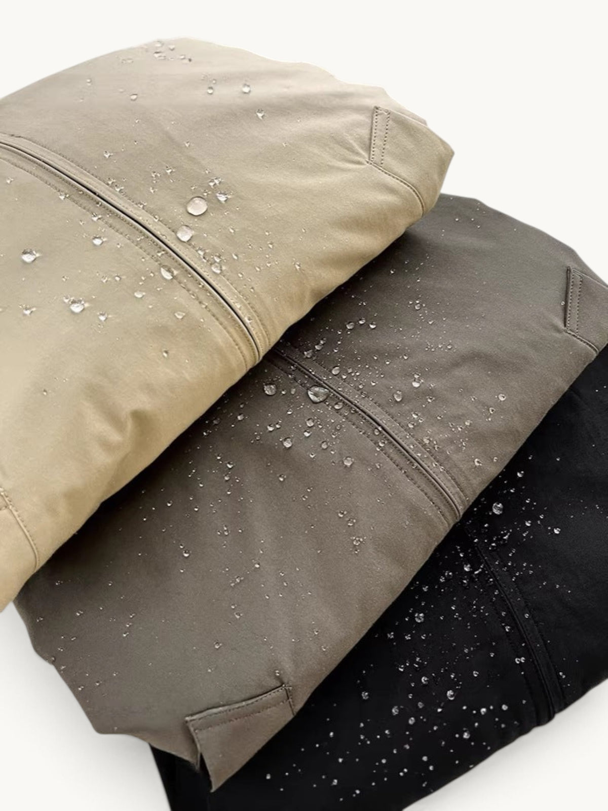 By Old Money water-resistant blouson jackets in beige, grey, and black with visible water droplets on the fabric