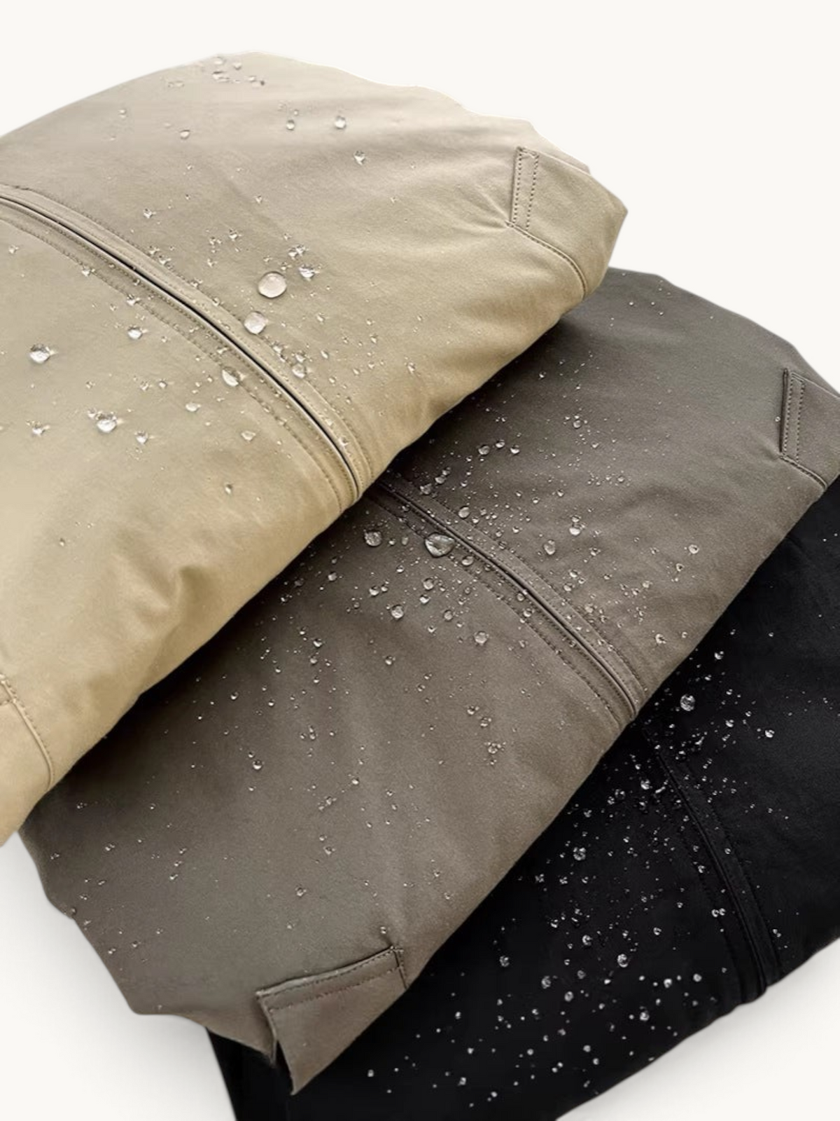 By Old Money water-resistant blouson jackets in beige, grey, and black with visible water droplets on the fabric