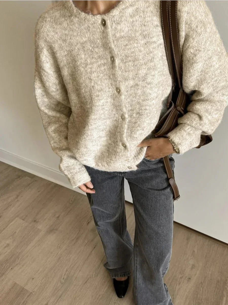 Cardigan boutonné beige à col rond, porté avec un jean gris