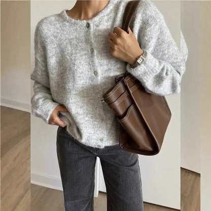 Cardigan boutonné gris clair à col rond, porté avec un sac en cuir