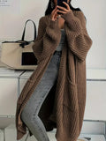 Cardigan long oversize marron en maille épaisse côtelée, porté avec un jean gris