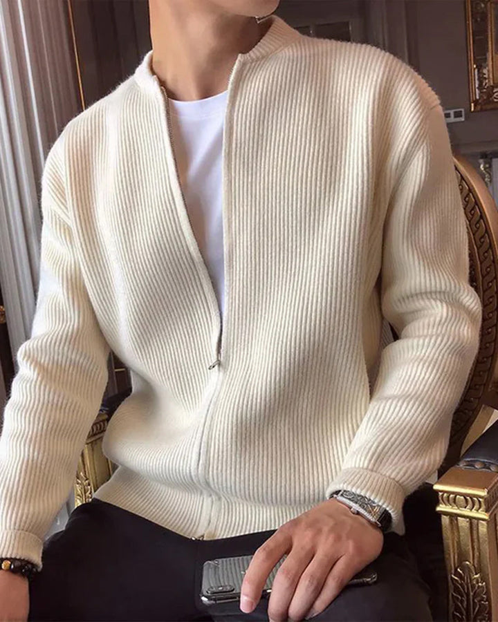 Homme assis en cardigan zippé écru côtelé, ouvert sur un t-shirt blanc, fauteuil doré