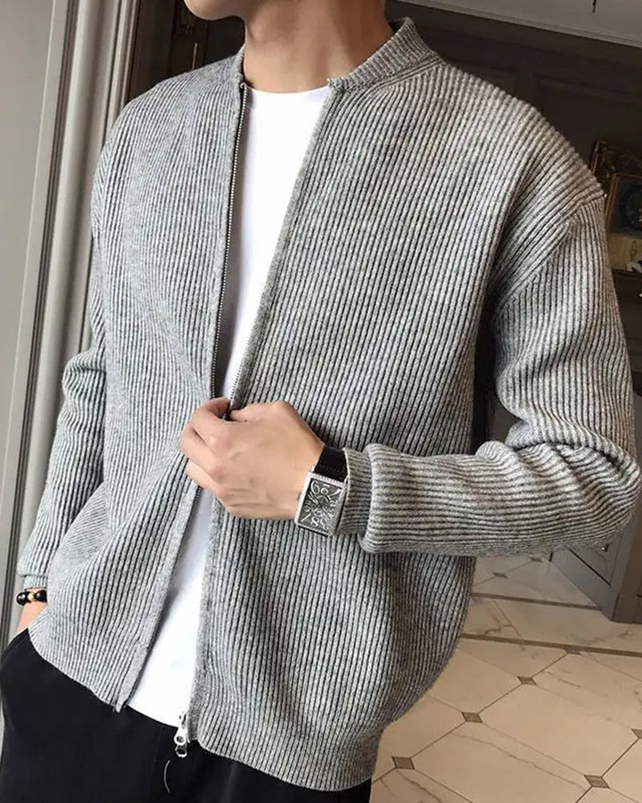 Homme ajustant son cardigan zippé gris chiné côtelé, ouvert sur un t-shirt blanc