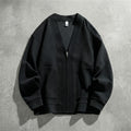 Cardigan zippé noir à col V posé à plat sur du béton, maille gaufrée et poches plaquées