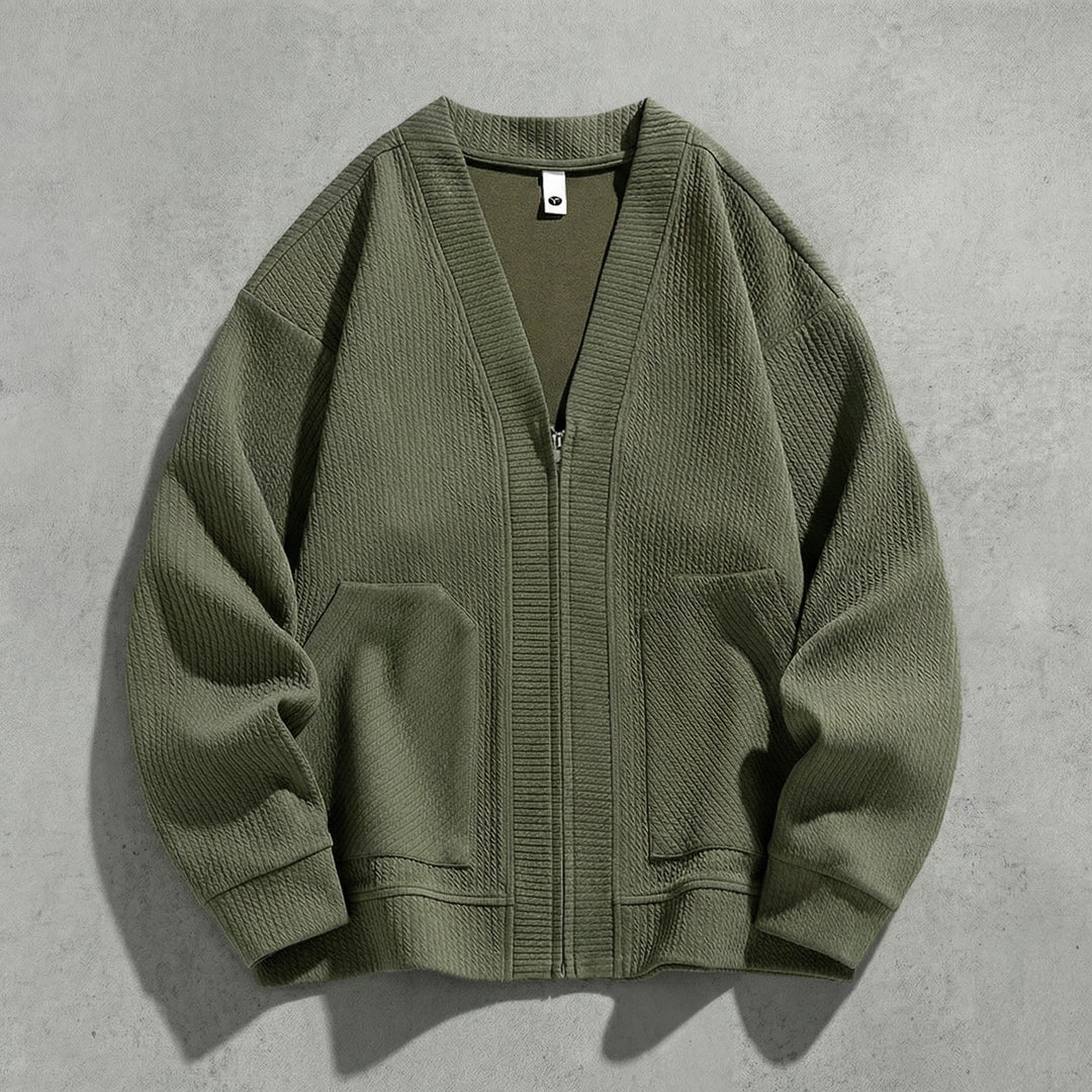 Cardigan zippé vert kaki à col V à plat sur du béton, maille gaufrée et poches basses