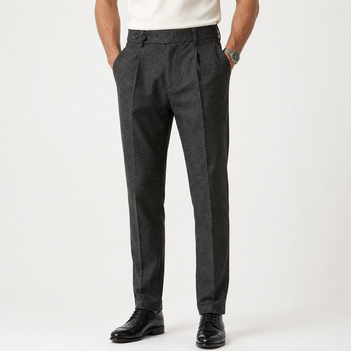 Charcoal wool tapered trousers with pleats and belt loops, worn by model