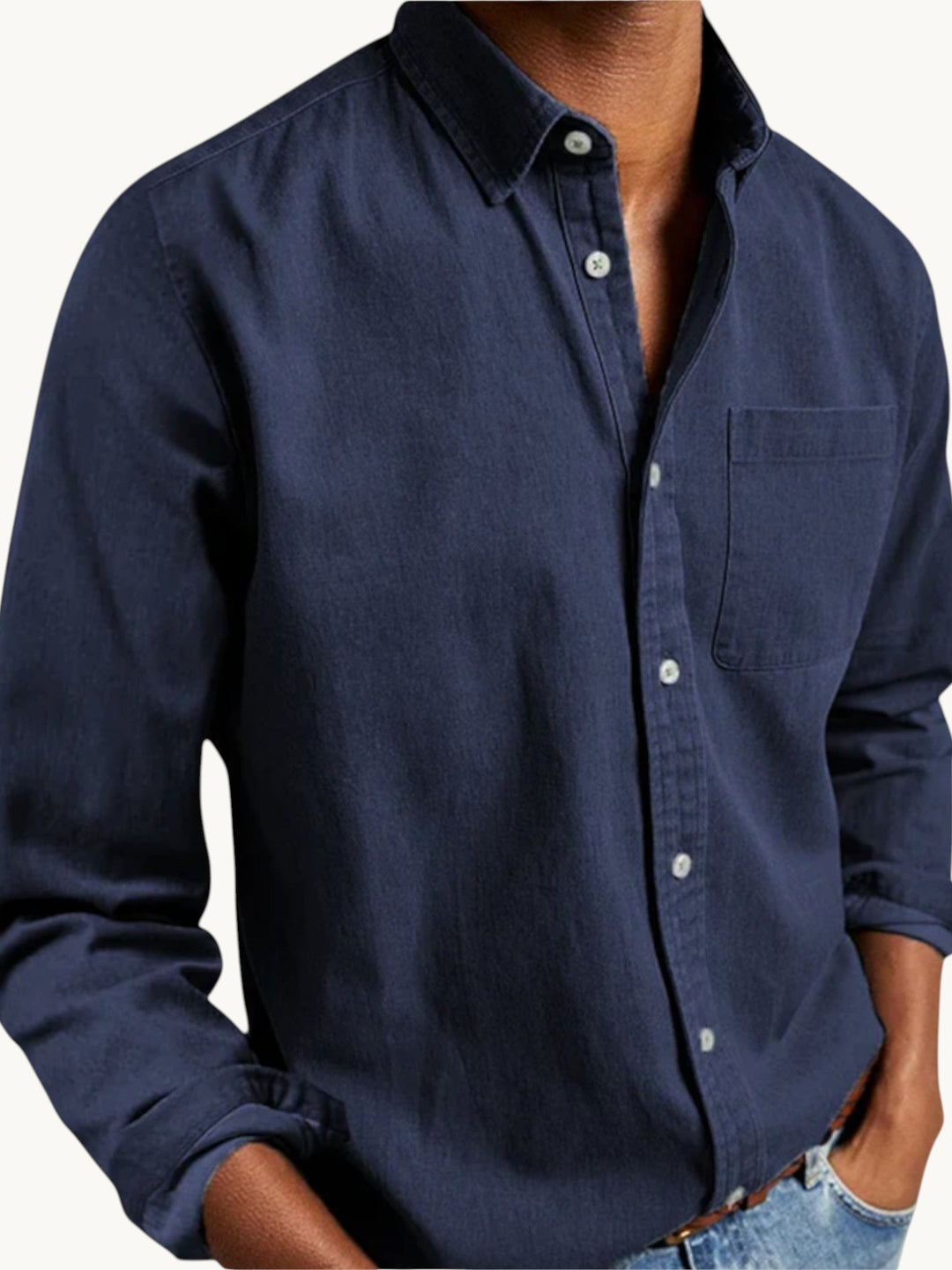 Chemise en denim bleu foncé à manches longues, col classique et poche poitrine, portée sur modèle homme