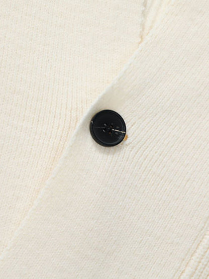 Gros plan sur un bouton noir et la maille écrue du cardigan