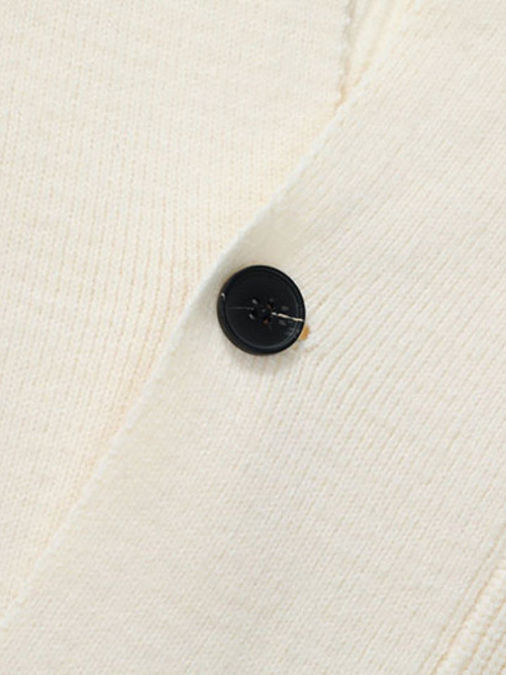 Gros plan sur un bouton noir et la maille écrue du cardigan