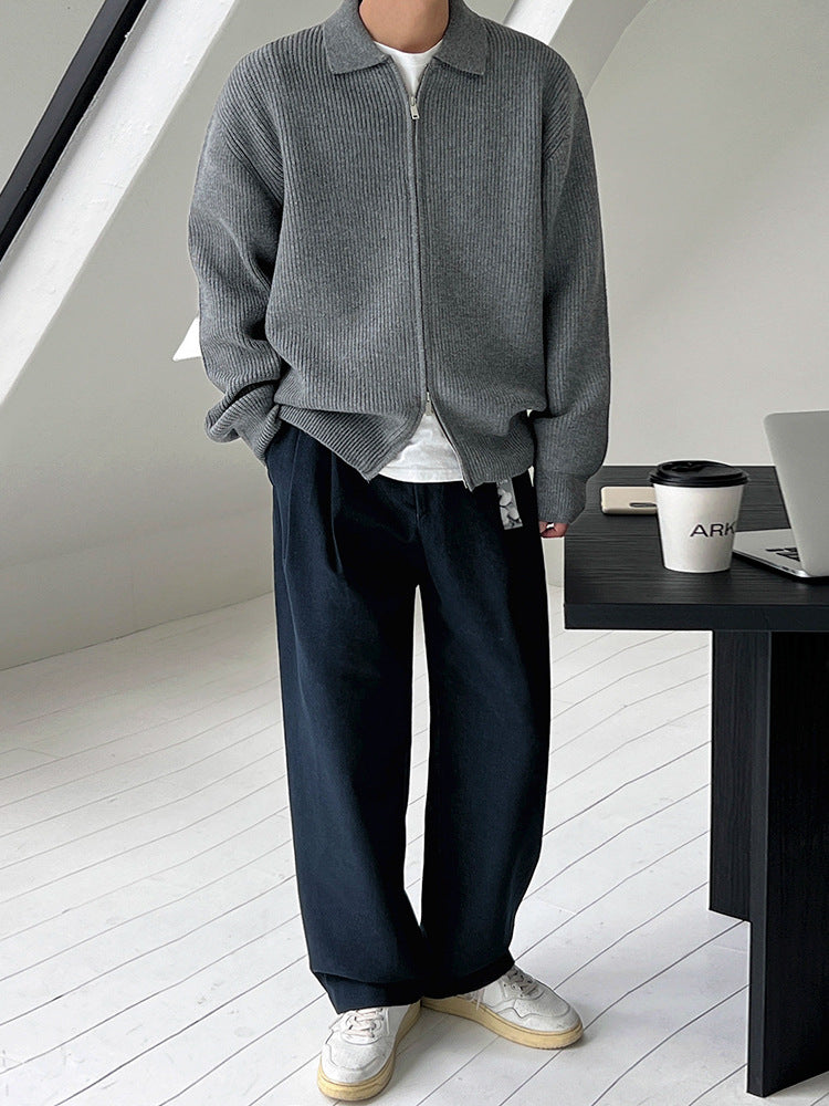 Veste en maille côtelée grise zippée, portée avec un pantalon ample, plein pied