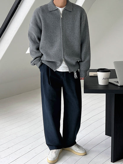 Veste en maille côtelée grise zippée, portée avec un pantalon ample, plein pied