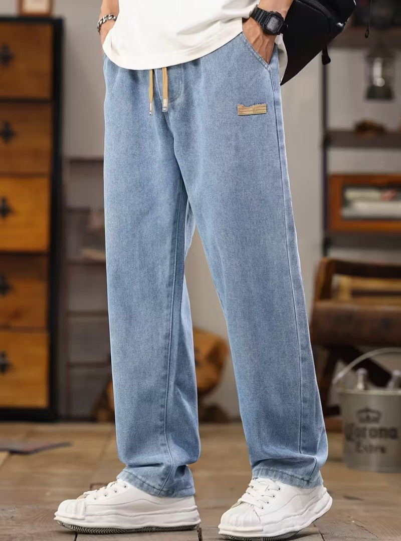 Jean large bleu clair à taille élastique et cordon beige, avec des baskets blanches