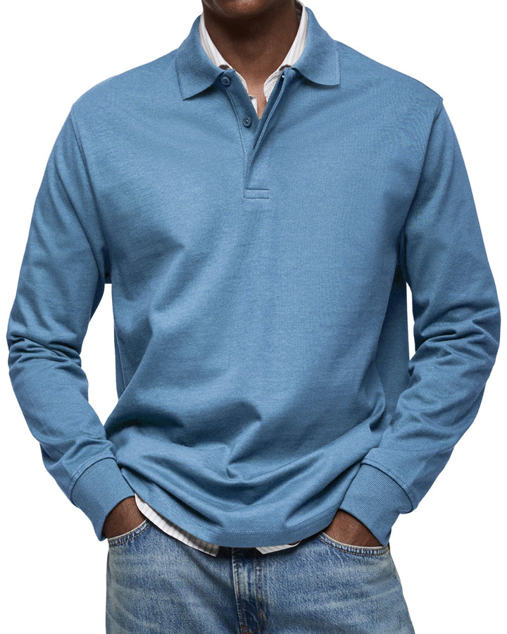 Polo à manches longues bleu denim, col ouvert sur une chemise blanche, poignets côtelés
