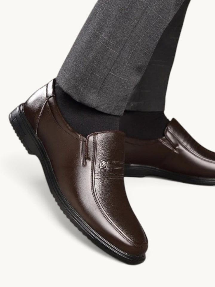 Mocassin en cuir marron semi-brillant, porté avec costume gris et chaussettes noires