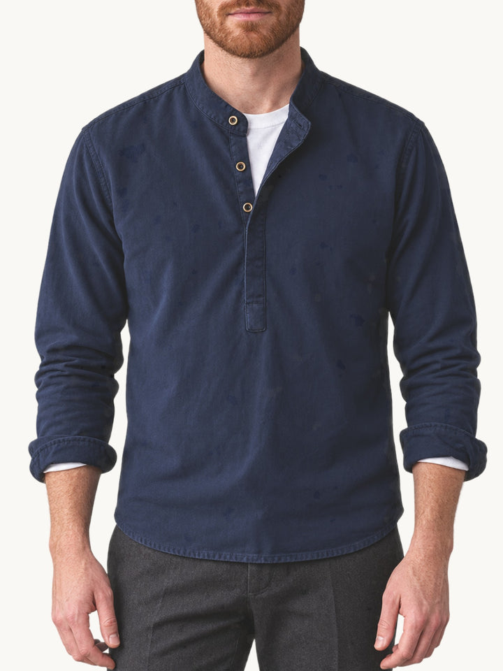 Chemise bleu marine à col montant portée par un homme, manches retroussées