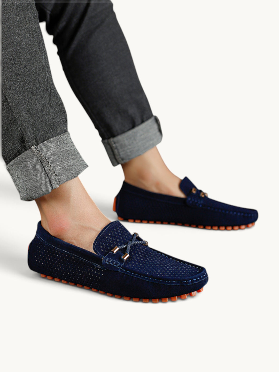 Mocassins en cuir perforé bleu marine portés avec un jean, semelle à picots orange