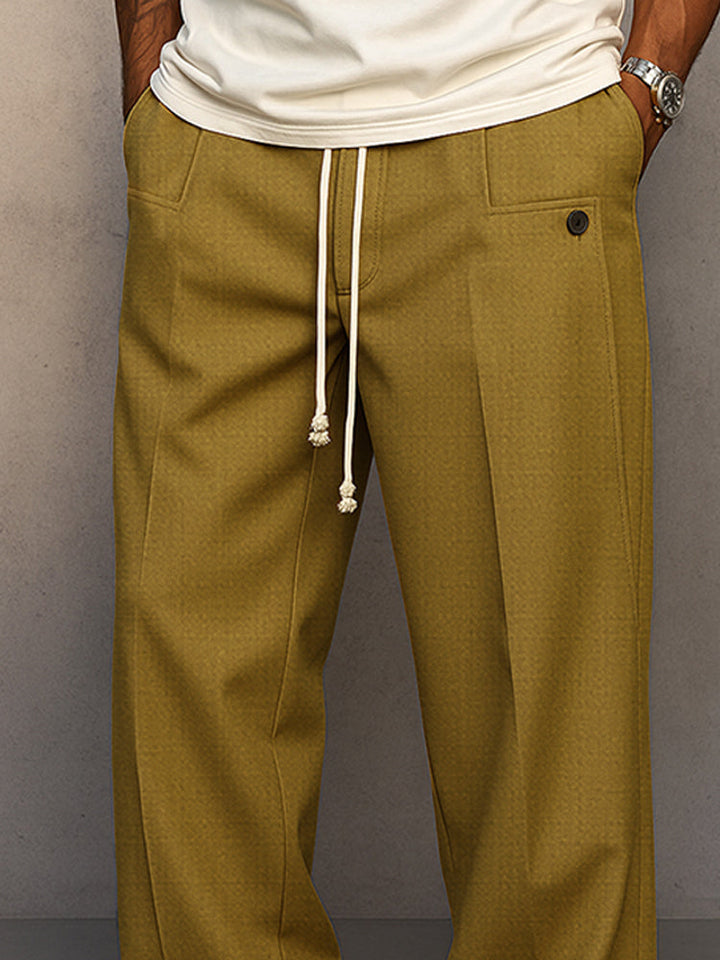 Gros plan sur la taille du pantalon moutarde : cordon écru, poche et bouton foncé