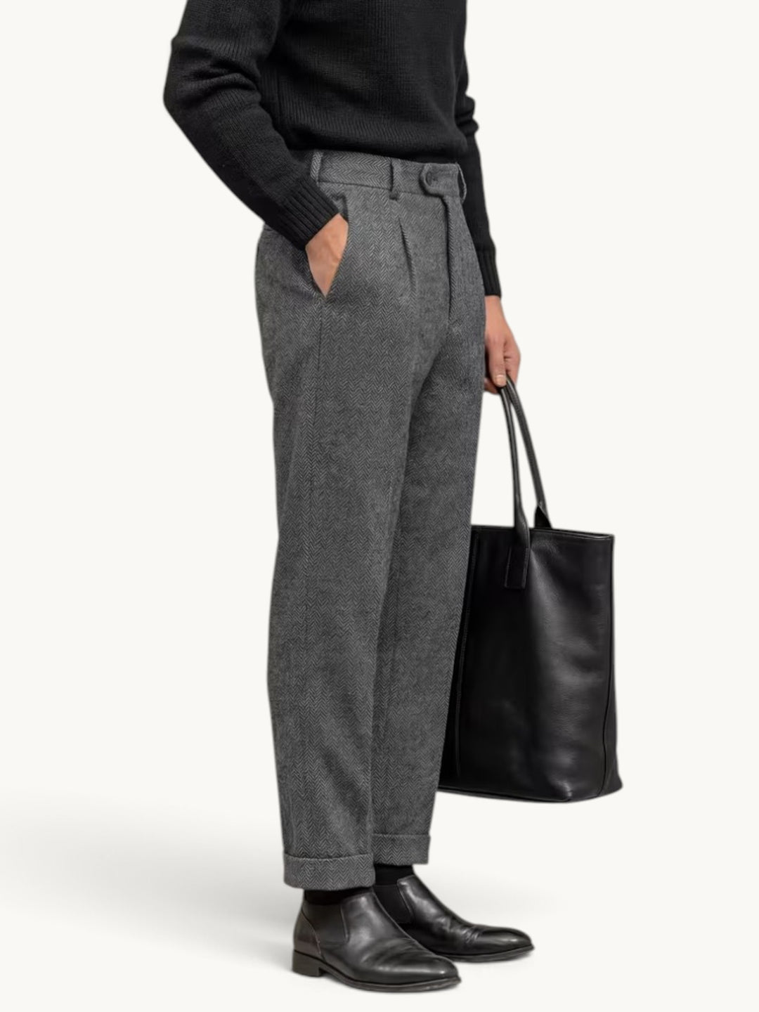 Pantalon habillé à pinces en chevrons gris porté de profil avec revers