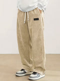 Pantalon large en velours côtelé beige, cordon écru et étiquette noire à la hanche