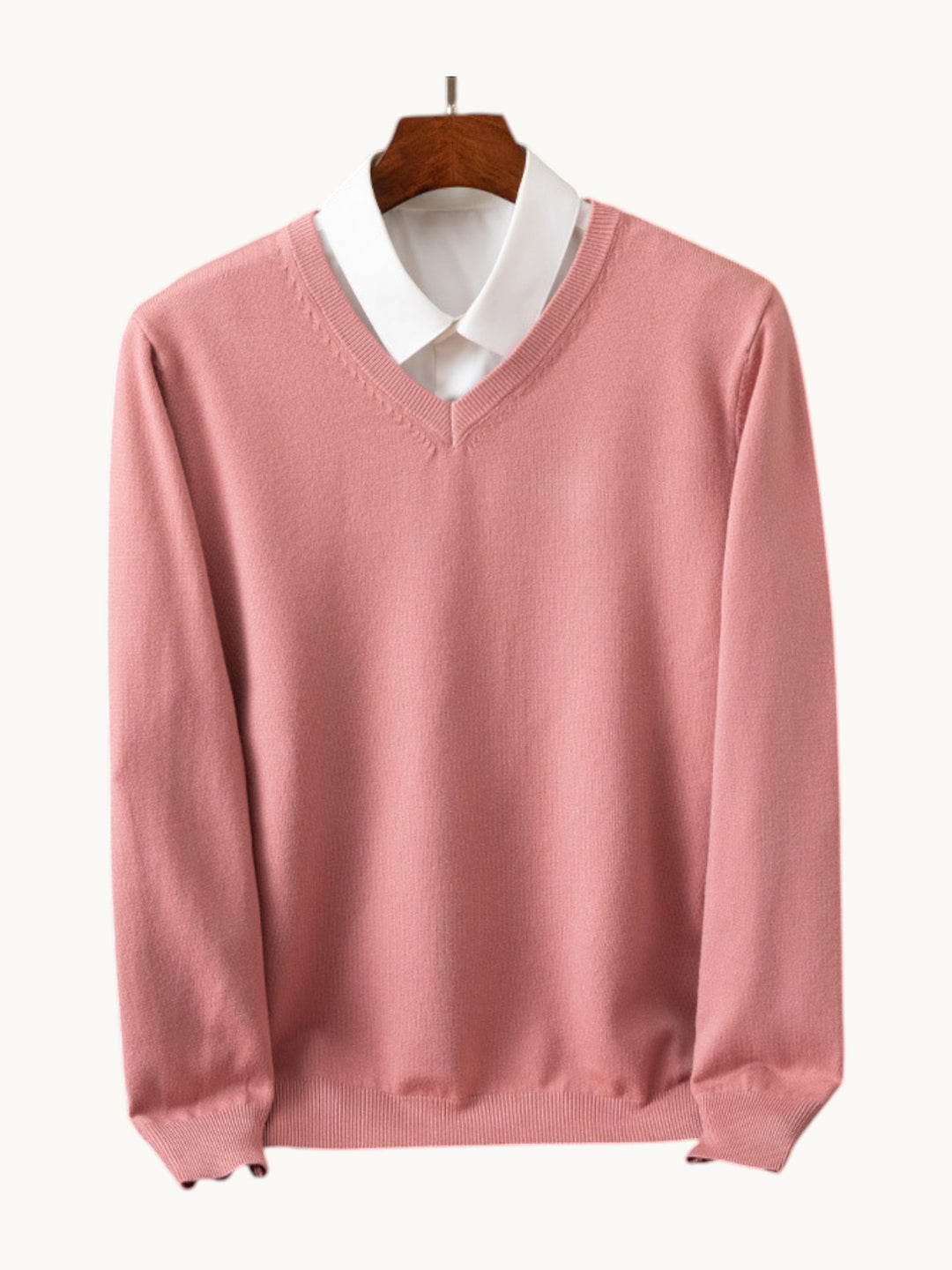 Pull en maille rose à col en V sur cintre, porté sur une chemise blanche
