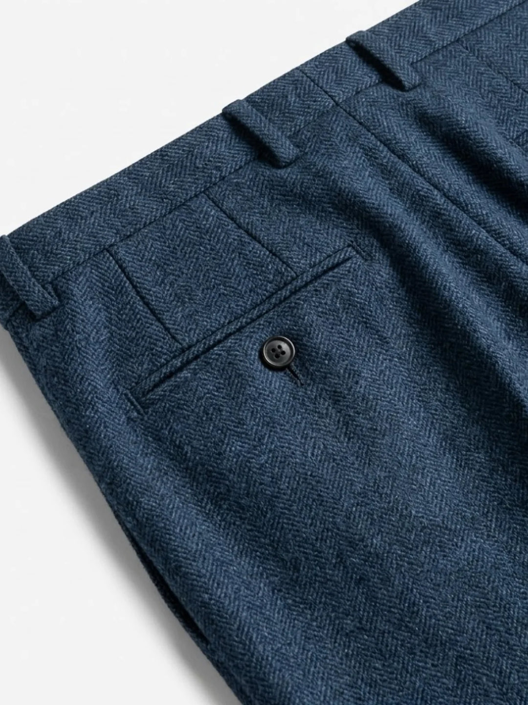 Gros plan sur la poche arrière boutonnée et les passants du pantalon en chevrons bleu