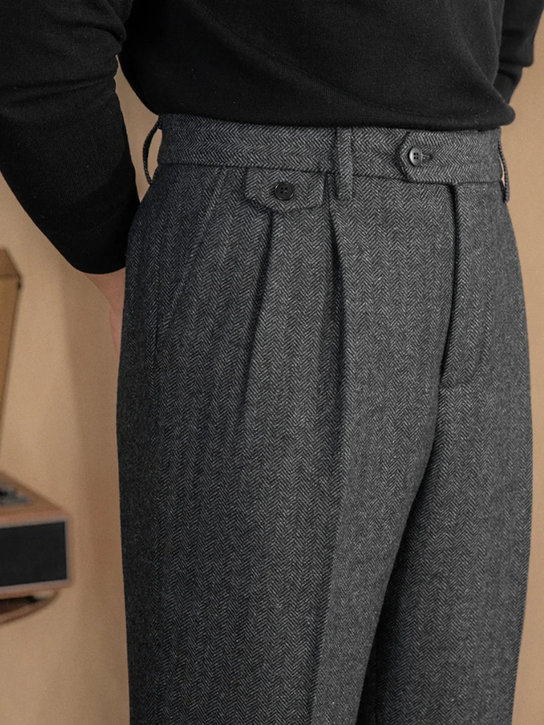 Pantalon à plis en chevrons gris porté avec un col roulé noir, vue de trois quarts