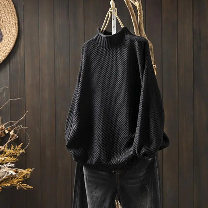Pull noir en maille texturée à col montant, présenté sur cintre