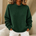 Pull vert en maille texturée à col montant, porté avec un pantalon blanc