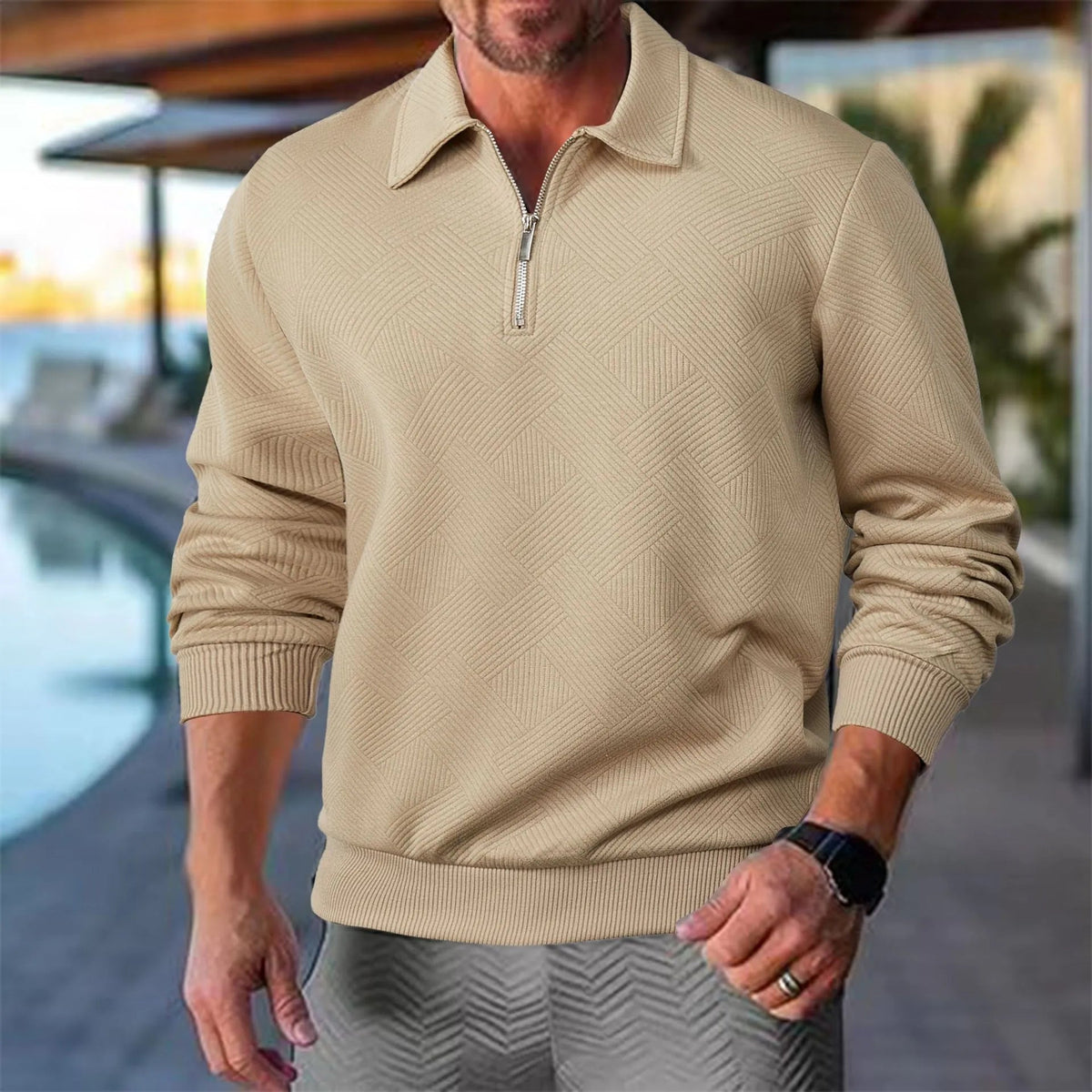 Pull à col polo kaki porté avec un pantalon gris au bord d'une piscine